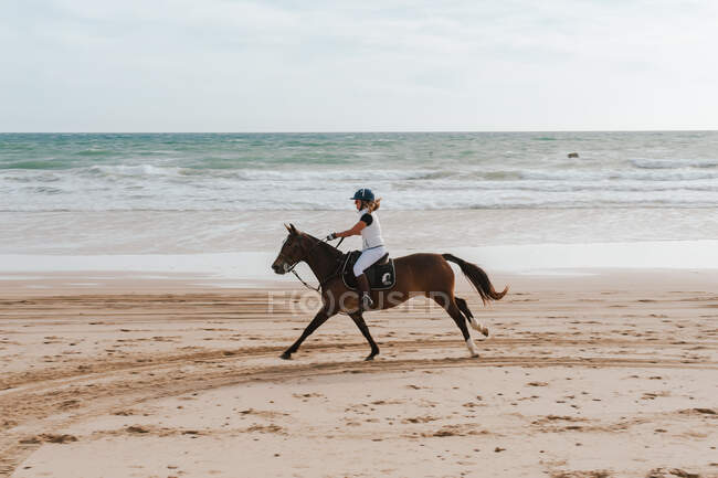 Woman riding Andalusian horse along beach in Spain — Stock Photo