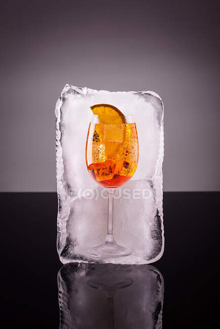 Стакан алкогольного напитка в большом кубике льда — стоковое фото
