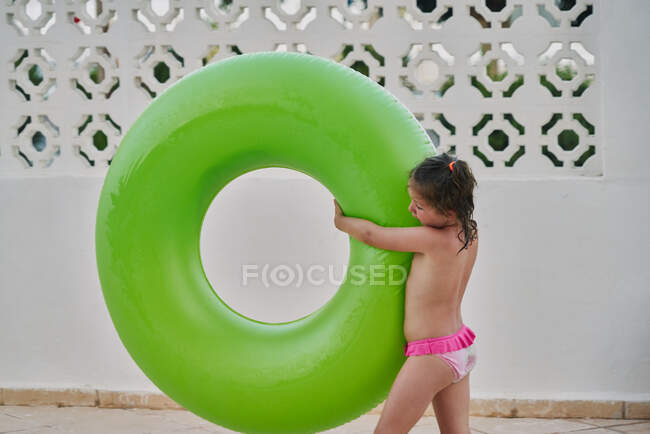 Girl carries a green float in her arms by the pool — Stock Photo
