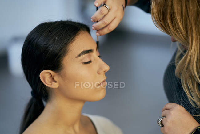 Primer plano de un maquillador tocando la cara de una modelo - foto de stock