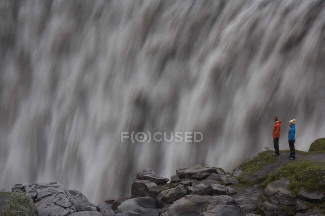 Casal em pé na frente da majestosa cachoeira Dettifoss — Fotografia de Stock