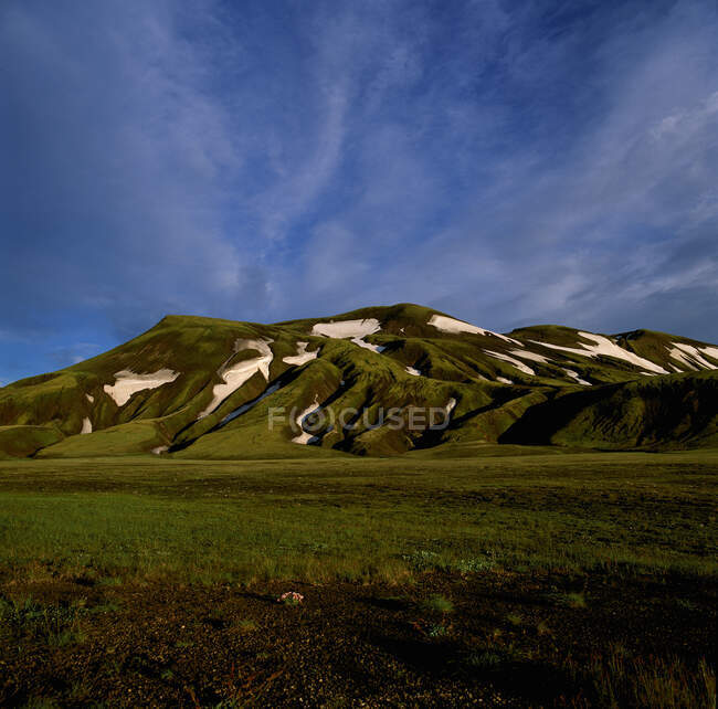 Relva verde no vale. nuvens bonitas. — Fotografia de Stock