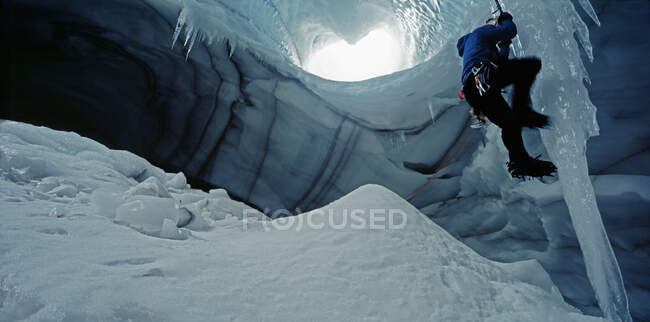 Ice climber scaling icicle in cave underneath Langjokull glacier — Stock Photo