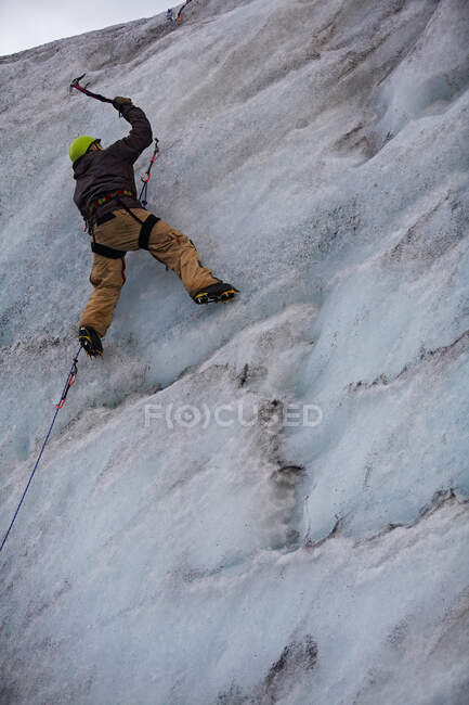 Young man climbing ice wall at Solheimajokull glacier in Iceland — Stock Photo