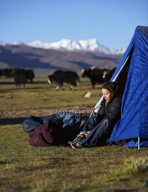 Mujer que se pone las botas en el campamento en el Tíbet - foto de stock