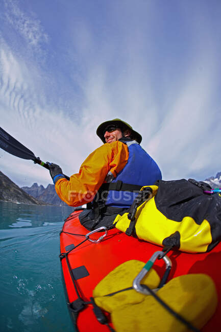 Homme voyageant sur un kayak de mer à travers les fjords de l'est du Groenland — Photo de stock