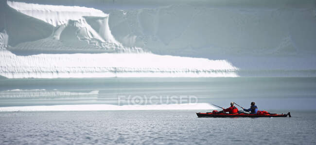 2 hombres viajando en un kayak de mar a través de los fiordos del este de Groenlandia - foto de stock