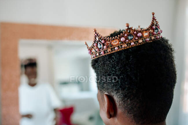 Afro-américain garçon portant bijoux couronne regarder dans miroir — Photo de stock