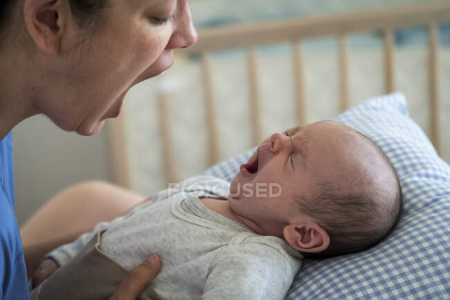 Mother with mouth open imitating yawning baby at home — Stock Photo