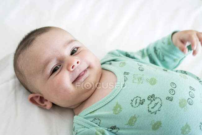 Close-up retrato de criança sorridente deitada na cama em casa — Fotografia de Stock