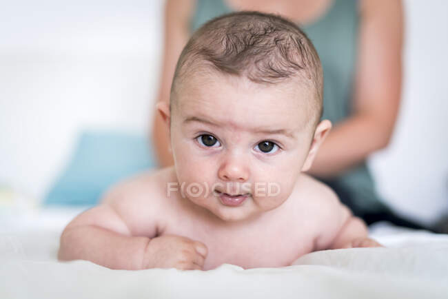 Retrato de primer plano de lindo bebé con ojos marrones acostado en la cama - foto de stock