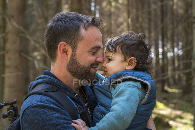 Primer plano de padre sonriente llevando lindo hijo mientras camina en - foto de stock