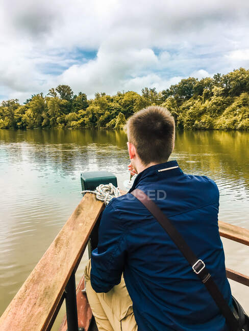 Menino na proa de um barco de madeira tendo uma bebida — Fotografia de Stock
