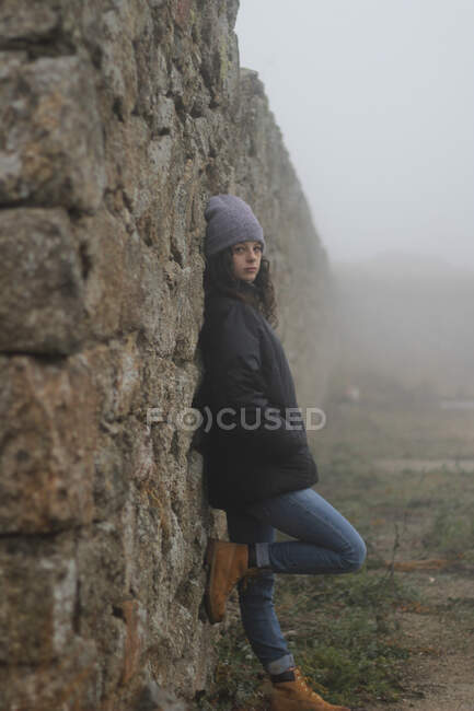 Young girl hatched on a stone wall — Stock Photo