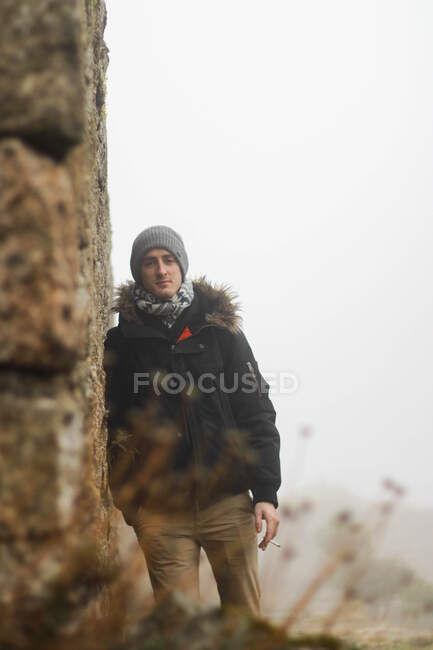 Menino com gorro e charuto inclinado na parede de pedra — Fotografia de Stock