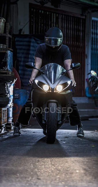 Uomo che mette in moto in un vicolo buio a Bangkok — Foto stock