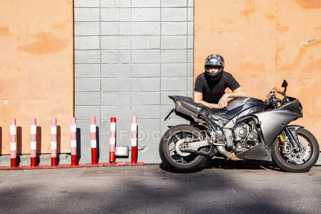 Hombre apoyado en su motocicleta en frente de Almacén en Bangkok - foto de stock