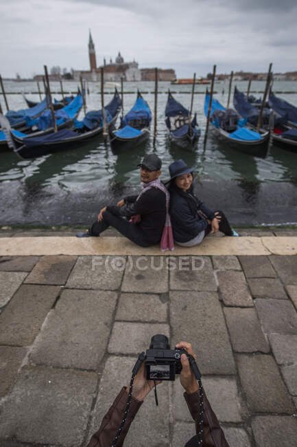 Woman taking picture of couple with gondola's in Venice — Stock Photo