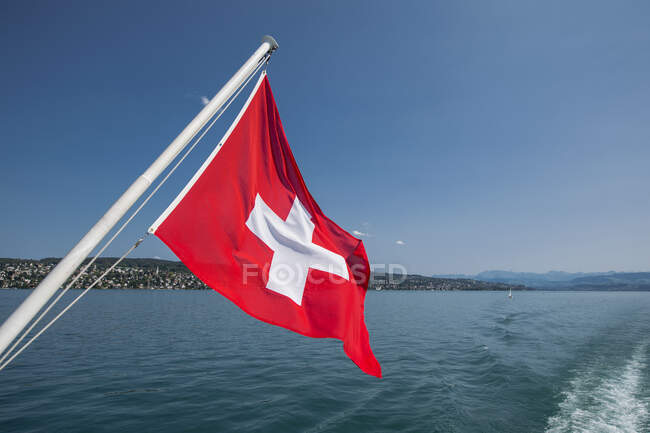 Bandera suiza en la parte trasera de un barco en el lago de Zurich - foto de stock