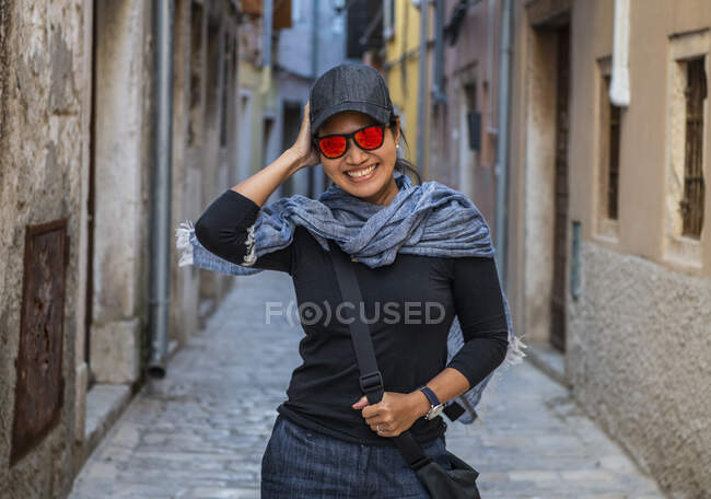 Mulher usando boné de beisebol e óculos de sol laranja no beco de rua — Fotografia de Stock