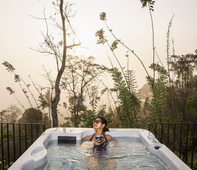 Woman enjoying a bath in a hot tub in the Sri Lankan highlands — early ...