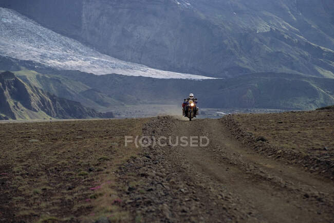 Человек едет на своем приключенческом мотоцикле по гравийной дороге в Исландии — стоковое фото