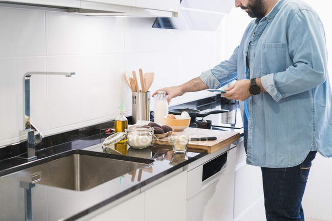 Мужчина готовит на кухне в джинсовой рубашке — стоковое фото
