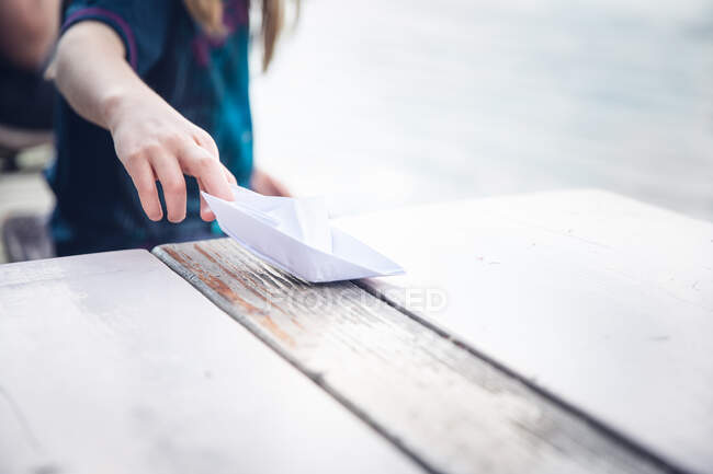 Дівчина сидить біля Сави, граючись на паперовому човні — стокове фото