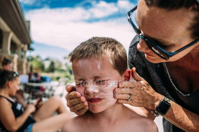 Mother putting sun screen on son's face — Stock Photo