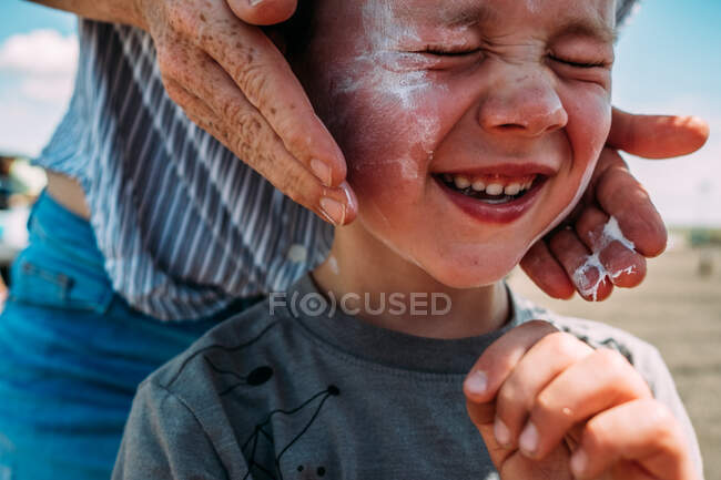 Nahaufnahme der Hände der Mutter beim Eincremen des Gesichts der Jungen — Stockfoto