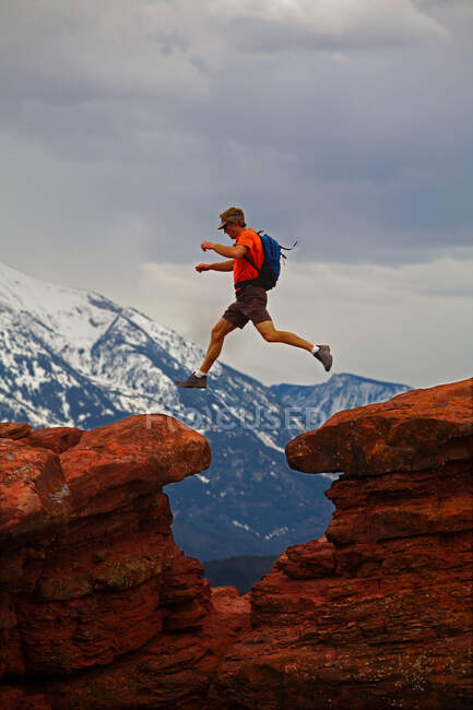 Man in a red jacket and a backpack on a rock — Stock Photo