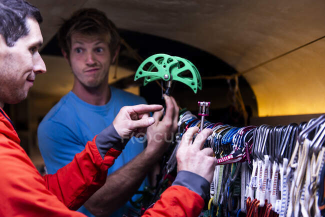 Man making funny face while trying to choose climbing gear to take — Stock Photo