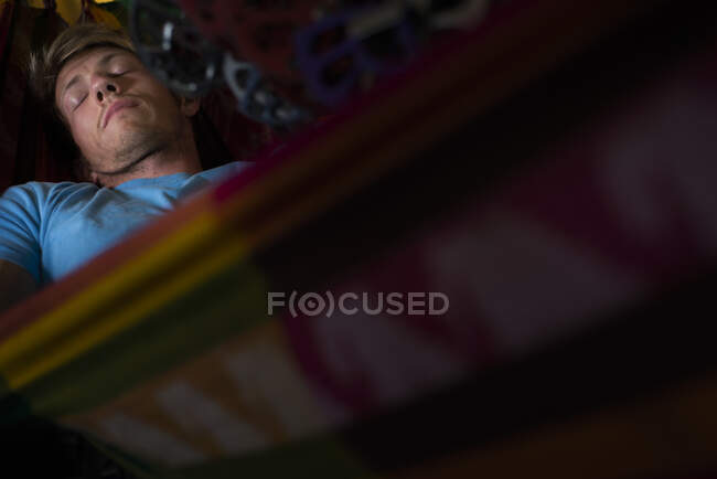 Homem dormindo na rede dentro do ônibus sob lotes de equipamento de escalada pendurado — Fotografia de Stock