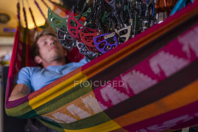 Man sleeping in hammock inside bus under lots of climbing gear hanging — Stock Photo