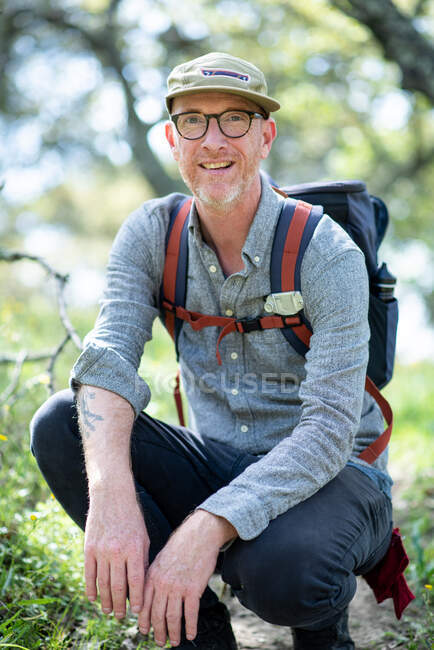 Portrait of backpacker kneeling on trail and smiling in California — Stock Photo
