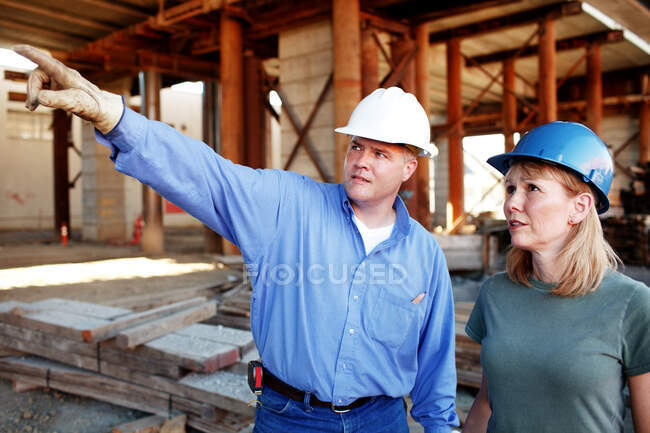 Hombre capataz de la construcción dando instrucciones a los trabajos de construcción - foto de stock