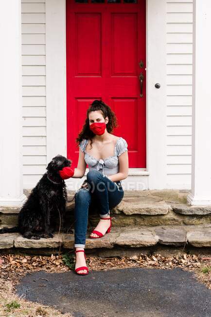 Young woman and dog wearing read mask during COVID-19 pandemic — Stock Photo