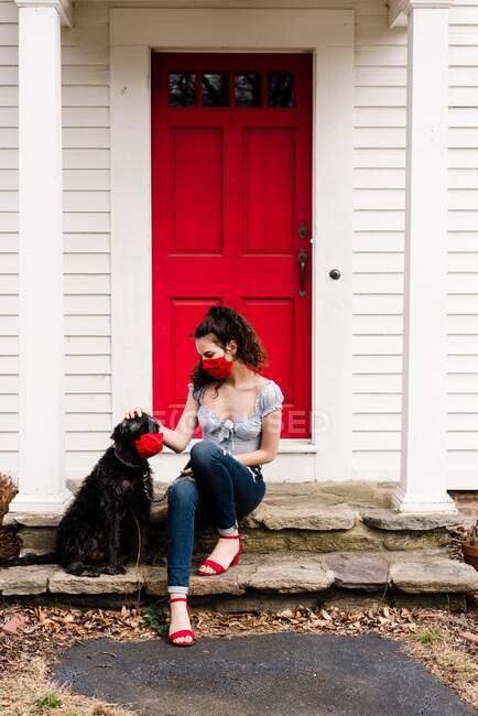 Молода жінка і собака у масці для читання під час пандемії COVID-19 — стокове фото