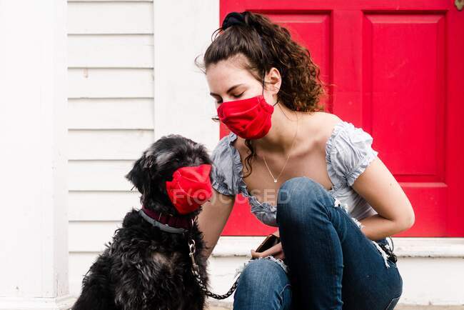 Jeune femme et chien portant un masque de lecture pendant la pandémie COVID-19 — Photo de stock