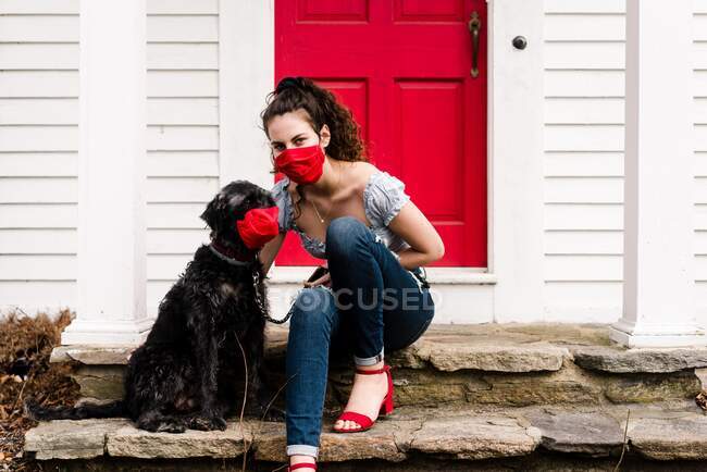 Молодая женщина и собака в маске для чтения во время пандемии COVID-19 — стоковое фото