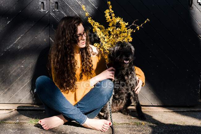 Bonita mujer joven con su perro a la luz del sol - foto de stock