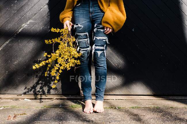 Junge Frau hält Forsythie im schönen Sonnenlicht — Stockfoto