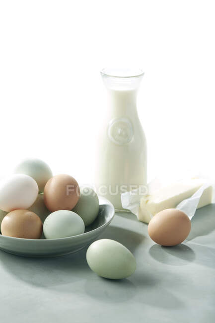 Eggs in the white bowl with chicken and milk in the glass jar — Stock Photo
