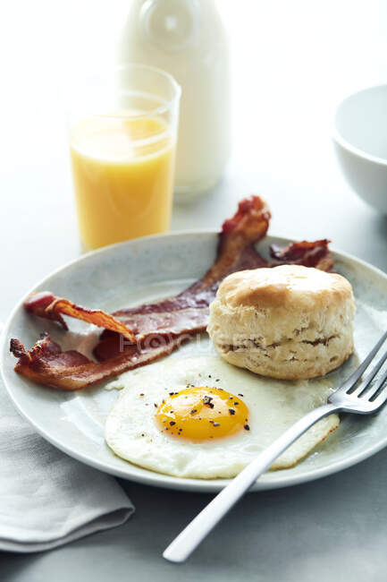 Fried egg and bacon with sausage, boiled eggs, toast, coffee, orange juice and toasts on white — Stock Photo