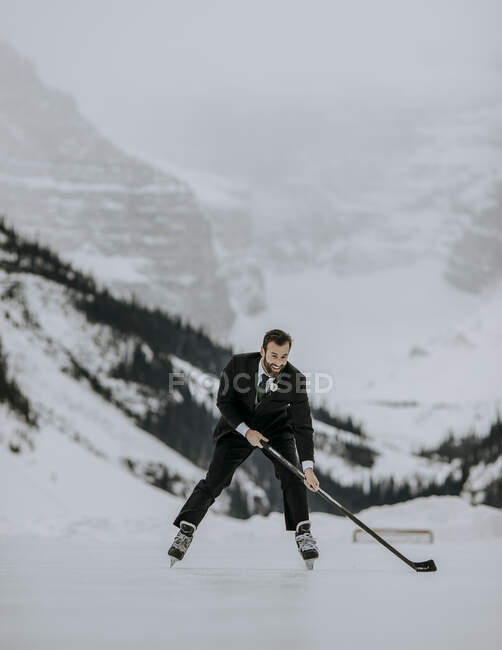 Молодой человек в костюме играет в хоккей зимой замороженный лед — стоковое фото