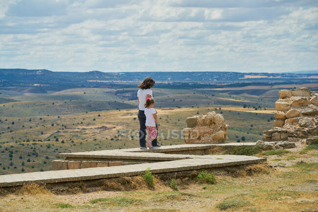 Madre e hija caminan sobre una pasarela en las montañas - foto de stock
