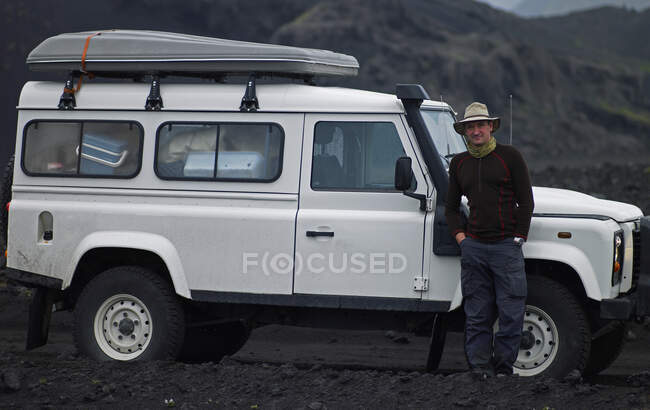 Hombre de pie junto a su vehículo todo terreno en Islandia - foto de stock