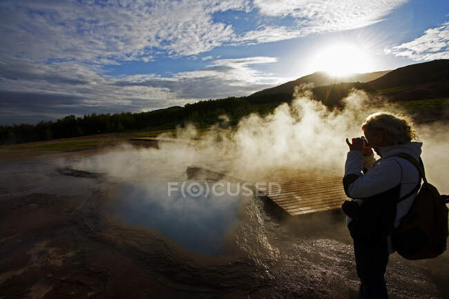 Зрелая женщина фотографирует геотермальный бассейн в Исландии — стоковое фото