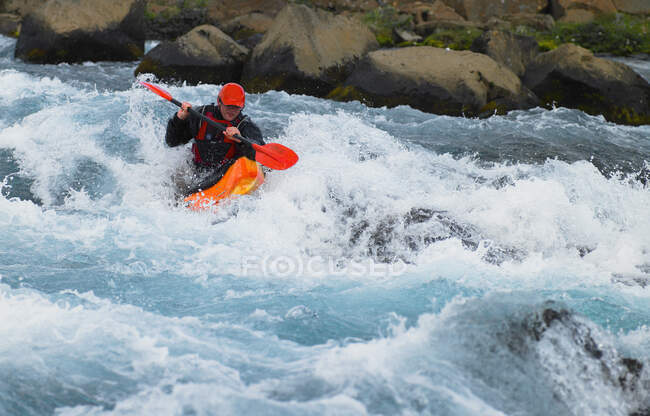 Un homme sur ses rapides de kayak d'eau vive dans une rivière islandaise — Photo de stock