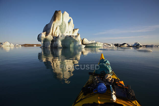 Poppa di un kayak da mare che galleggia verso un iceberg su una laguna ghiacciata — Foto stock